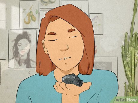 A woman with her eyes closed, holding a rock up close to her face.